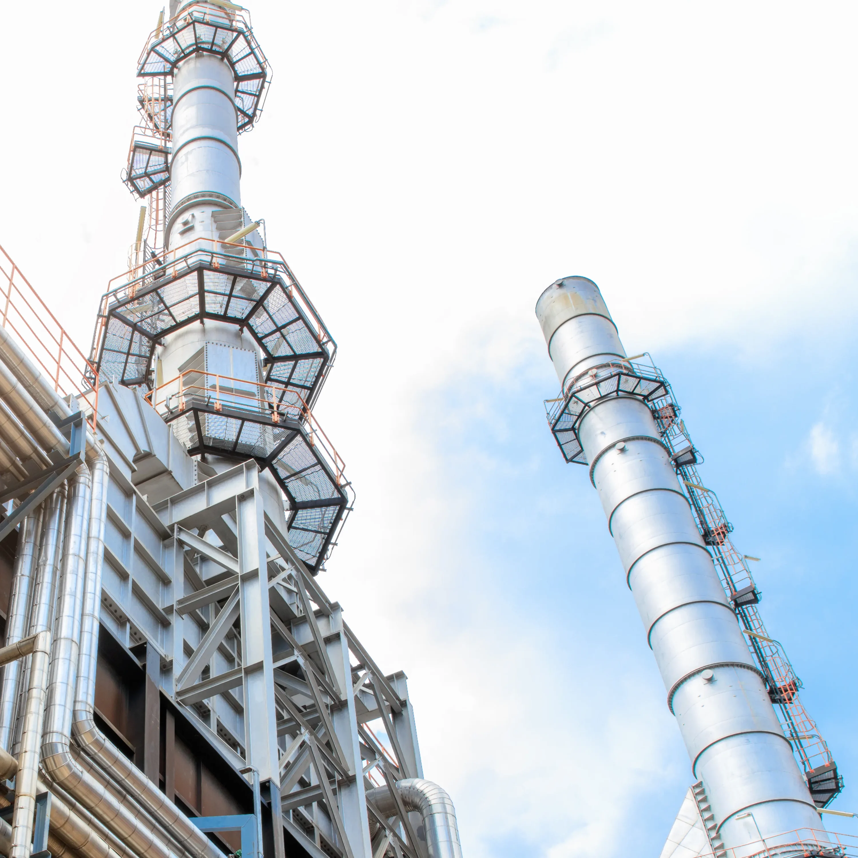 A gleaming petrochemical plant on a clear day, with silver tanks and chimneys, where isolation valves silently ensure safety and operational integrity.
