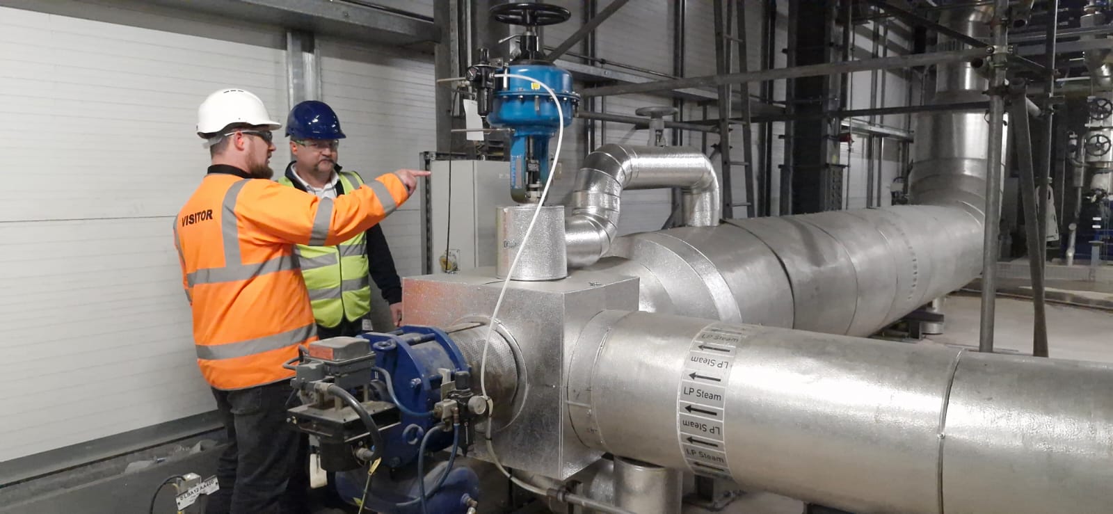 Engineers inspecting a valve and piping system at a waste-to-power facility, ensuring optimal performance and safety
