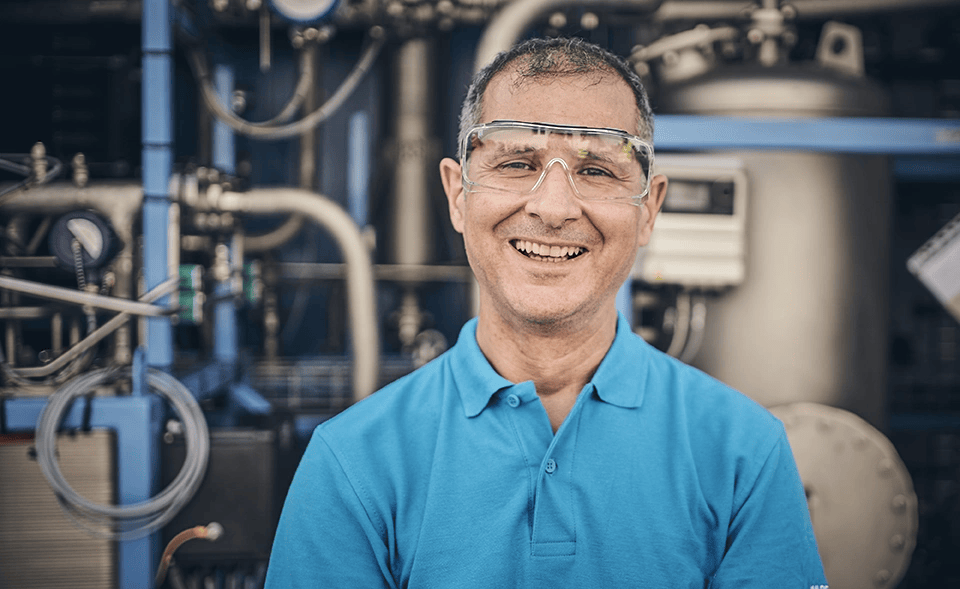 An engineer at the IMI VIVO site in Italy proudly poses infront of a green hydrogen electrolyser