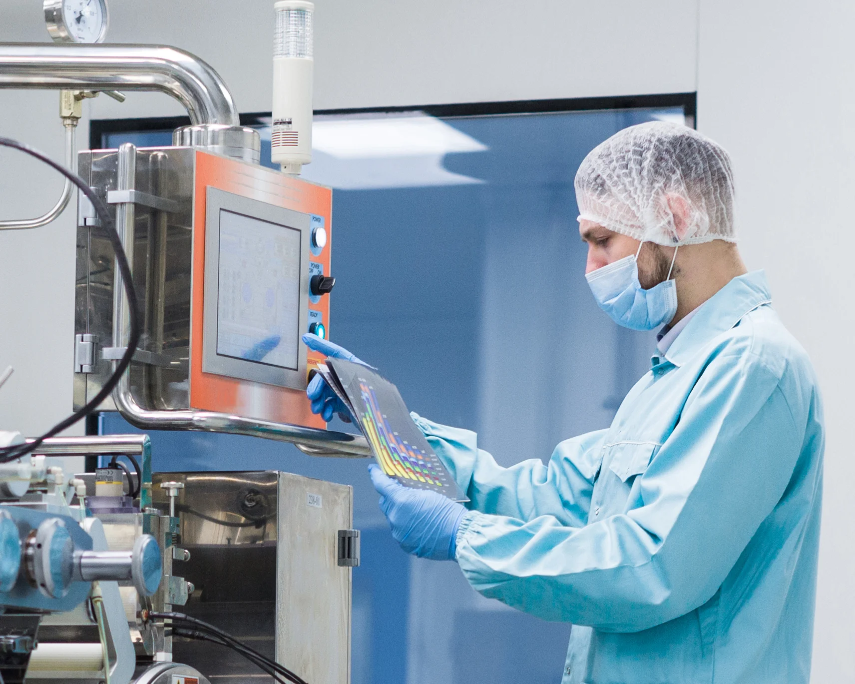 In the pharmaceutical industry, a focused man operates a processing machine, ensuring precise manufacturing of medications