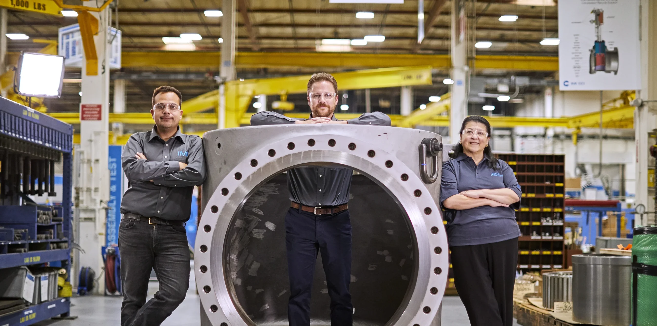 Three experts from IMI Americas in RSM confidently display their mastery of control valve technology, striking a pose in and around a large control valve body, exemplifying IMI's industry-leading expertise.