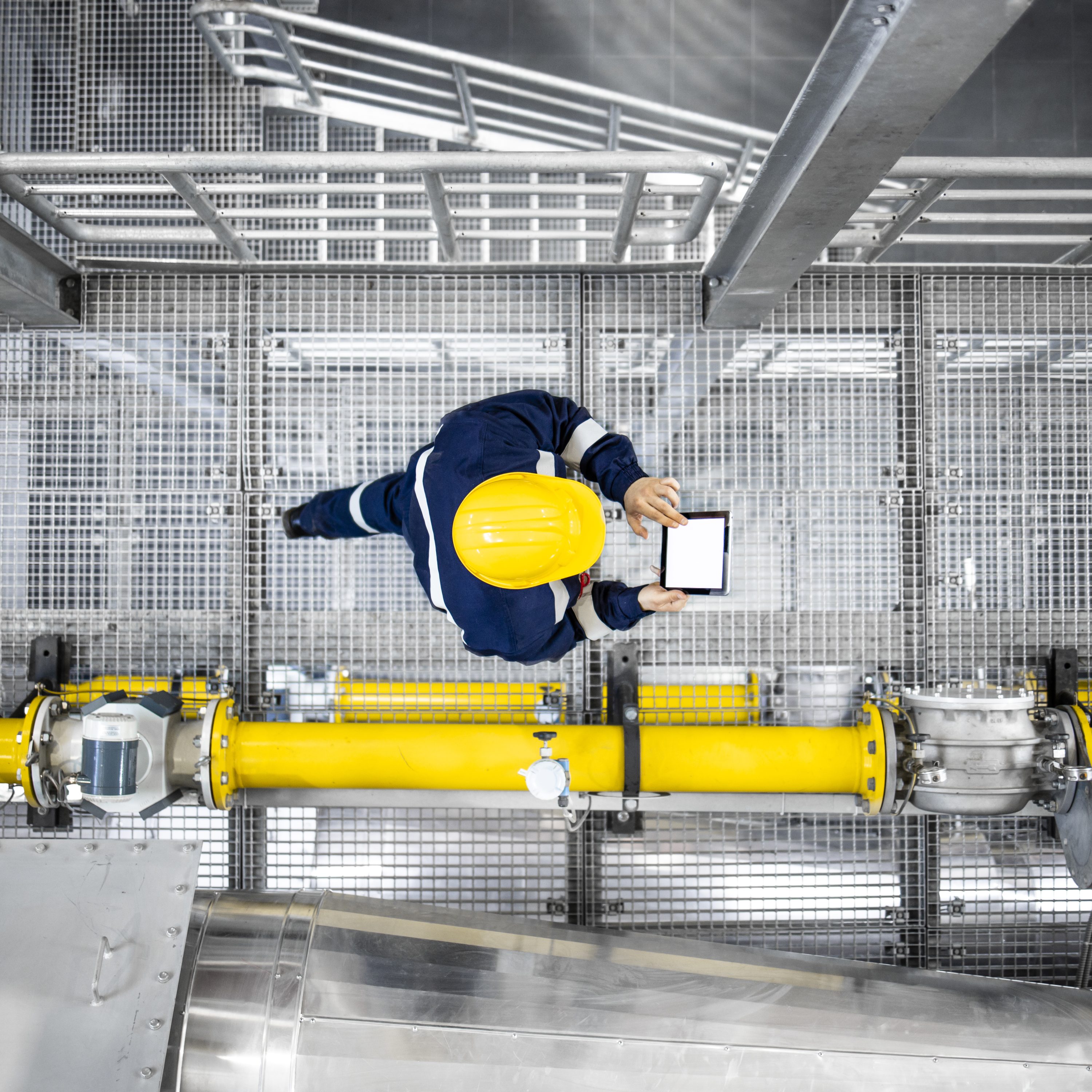 Man on oil platform uses analytics to measure performance, monitor operations, detect anomalies, and optimize efficiency, safety, and profitability.