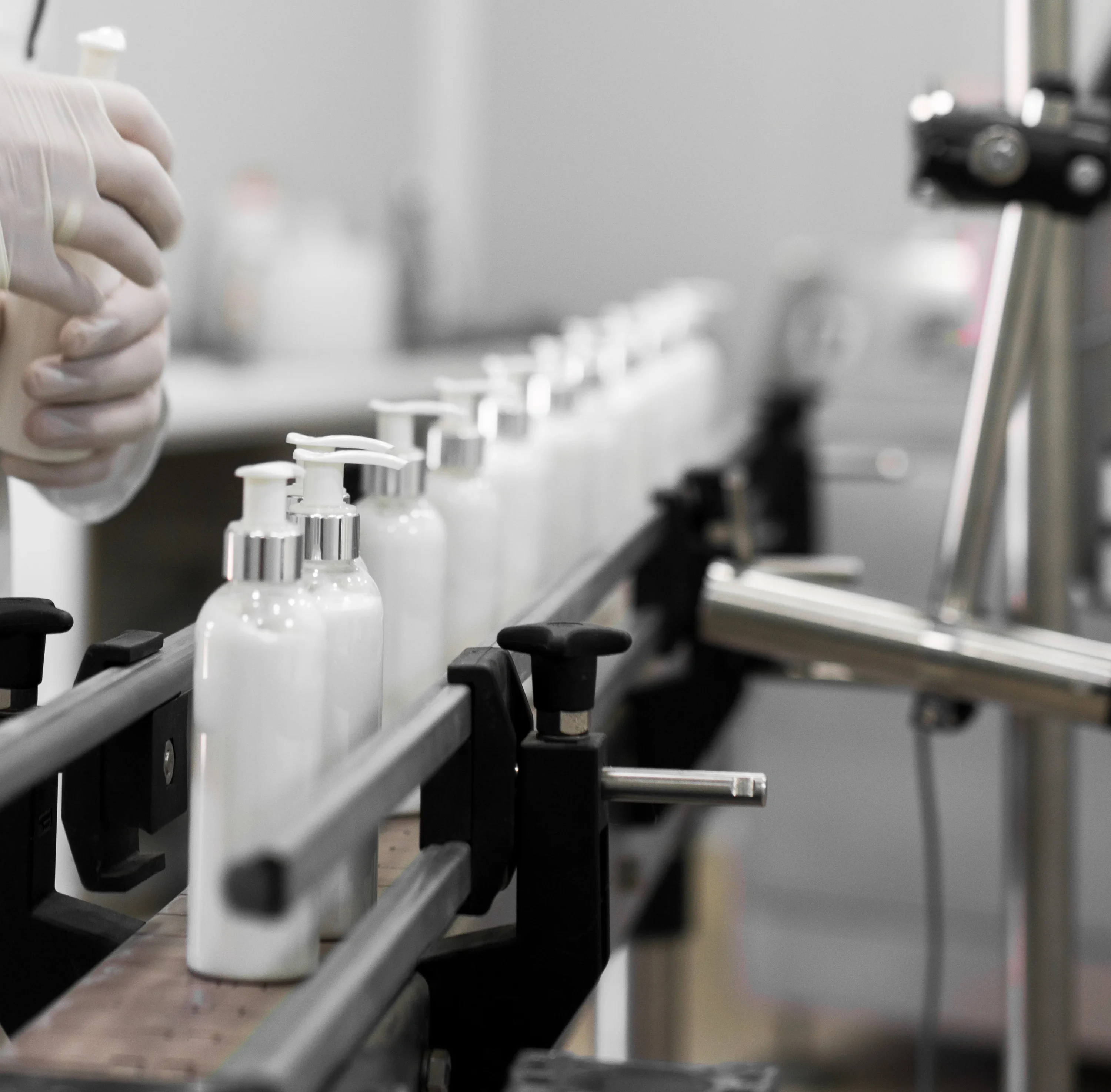 A worker in the cosmetics industry selects a bottle of liquid soap from a neatly arranged row on a fabric production line.