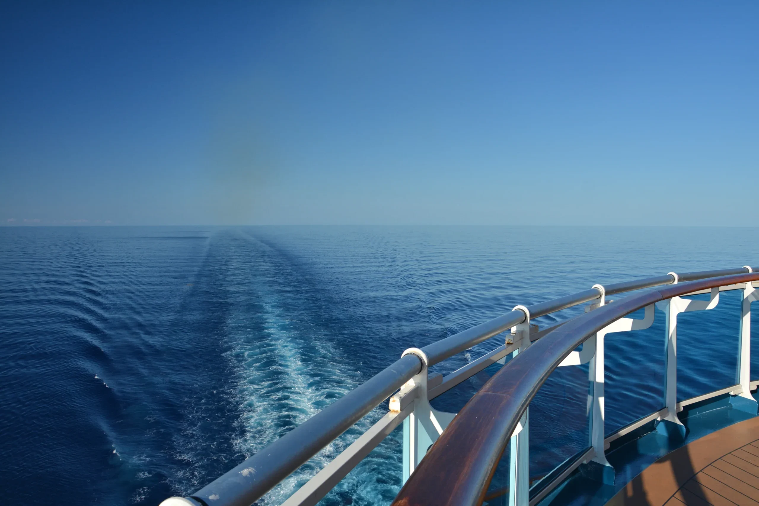 At the rear of the cruise ship, a serene view of the sea and its wake unfolds, offering tranquility and a sense of boundless exploration.