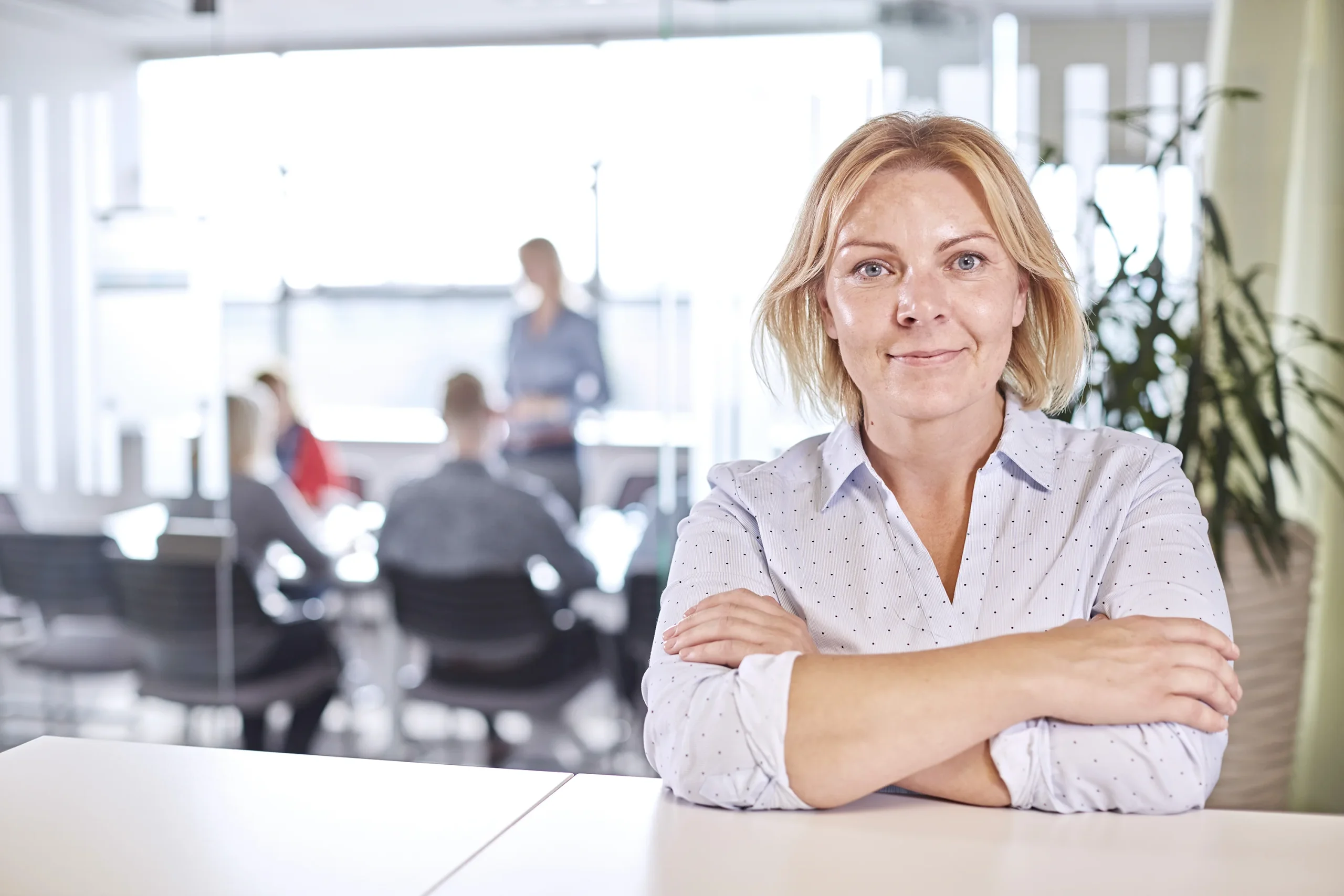 Confident woman strikes a pose amidst a vibrant meeting, showcasing active participation in a modern, productive setting.